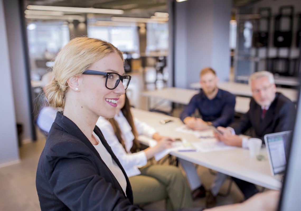 smiling-young-businesswoman-front-her-team-giving-presentation